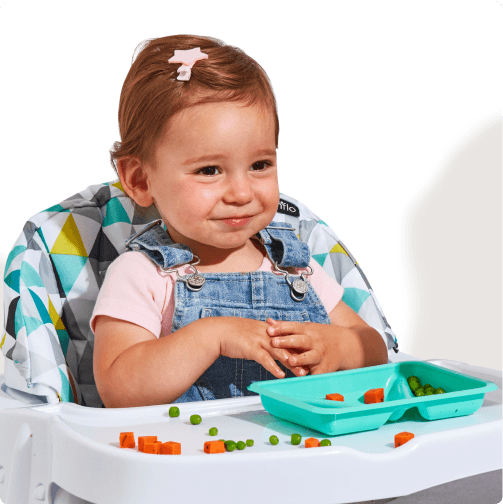 An 18 month old girl sits in a high chair with a tray of Little Spoon Biteables, which contain small-diced pieces of vital vegetables and proteins for young eaters.